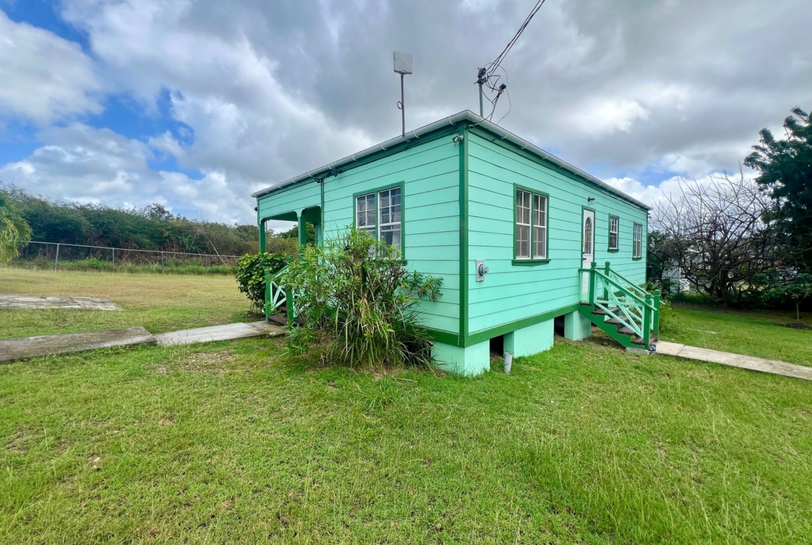 Front view of Emerald Breeze Cottage with lush greenery.