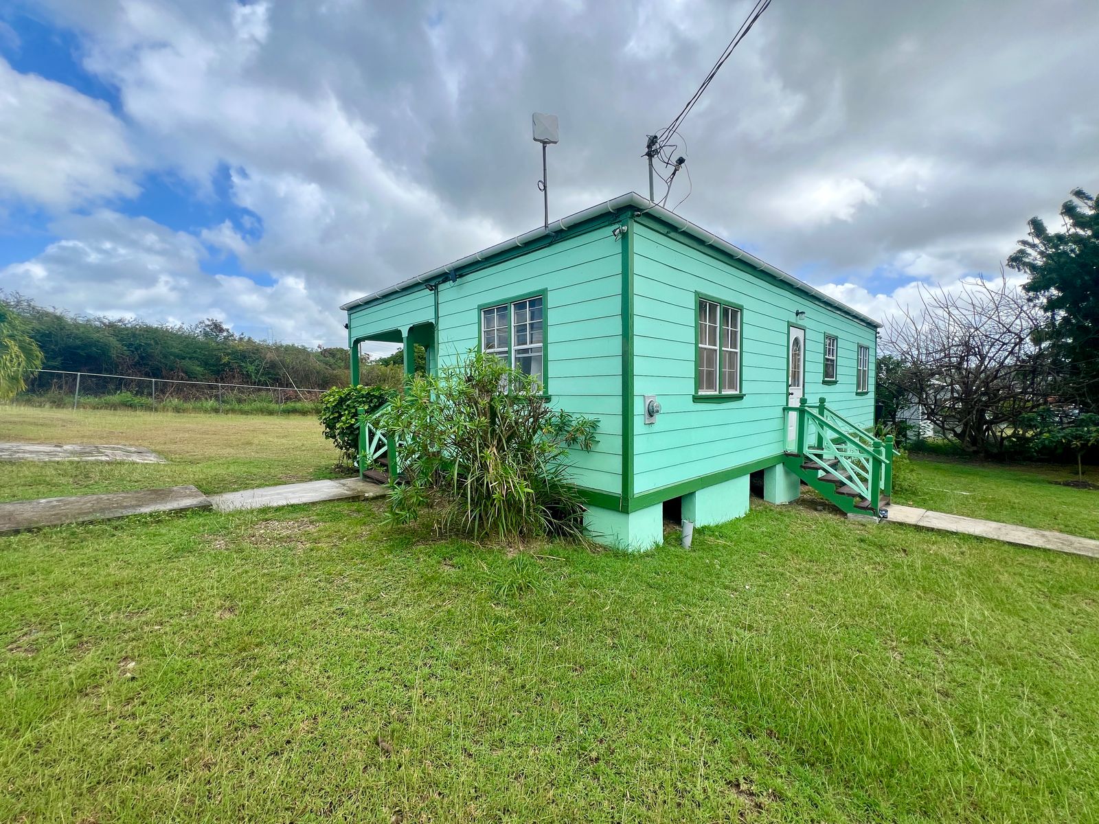 Front view of Emerald Breeze Cottage with lush greenery.